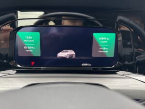 Digitales Autodisplay in einem Fahrzeug, zeigt Uhrzeit, Datum und Kilometerstand in grün.