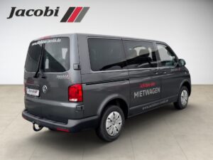 Grauer Volkswagen-Transporter mit "Ich bin ein Mietwagen" Text, Logo von Jacobi oben links.