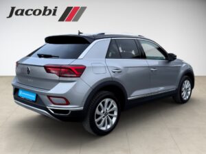 Silberner Volkswagen-SUV von der Seite, rotes Rücklicht, schlichte Umgebung, "Jacobi"-Logo oben links.