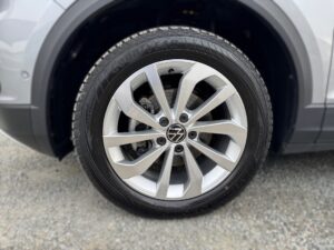 Nahaufnahme eines silbernen Autoreifens mit VW-Logo und Goodyear-Reifen auf grauem Kieselboden.