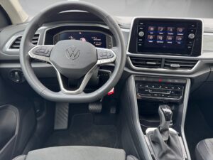 Innenraum eines VW-Autos, graue Sitze, modernes Armaturenbrett, digitales Display, Lenkrad.