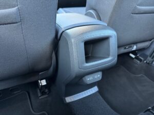 Rückseite eines Autositzes mit Mittelkonsole und USB-Anschlüssen, grauer Stoff, minimalistisch.