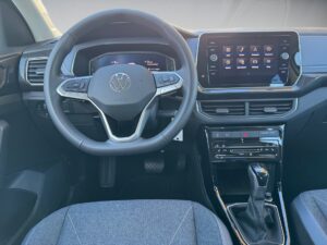 Lenkrad und Armaturenbrett eines VW-Fahrzeugs mit Touchscreen und grauem Sitz.