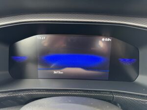 Digitales Armaturenbrett mit blauem Display, zeigt Uhrzeit "13:27" und Temperatur "0°C" an.