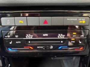 Farbdisplay des Fahrzeug-Klimasystems zeigt Temperatur, Auto- und Sync-Modus, Tasten umrahmt.