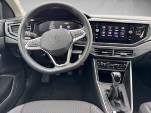 Innenraum eines VW-Autos, schwarzes Lenkrad, Touchscreen-Display und Schalthebel sichtbar.