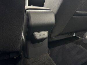 Rücksitz eines Autos mit grauem Stoff und einem USB-C-Doppelanschluss am Mittelkonsolenrücken.