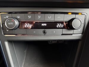 Klimaanlagensteuerung in einem Auto, zeigt 22°C und Auto-Modus, silberne Knöpfe, USB-Anschlüsse.