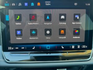 Autoinfotainment-System auf Deutsch, mit Apps, blauer Oberfläche und Temperaturanzeige.