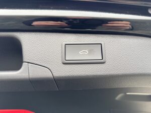 Kofferraumöffnungsschalter im Auto mit symbolisiertem Kofferraumsymbol auf grauem Panel.