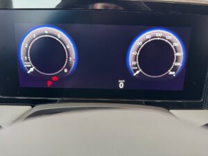 Digitales Tachometer in einem Auto, zeigt km/h und Umdrehungen, rote und blaue Akzentfarben.