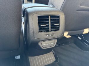 Lüftungsschlitze im Auto mit zwei USB-Anschlüssen darunter, schwarze Innenausstattung, modernes Design.