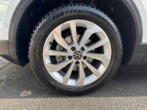 Ein silbernes VW-Rad mit Goodyear-Reifen, moderne Speichen, Asphalt-Hintergrund.