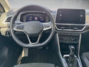 Lenkrad eines Volkswagen-Autos, schwarze Farbe, mit Armaturenbrett-Anzeigen und Multimedia-Bildschirm.