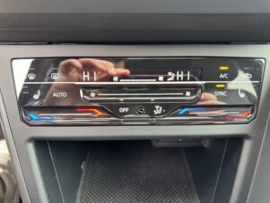 Digitale Klimaanlage-Steuerung in einem Auto mit Touch-Buttons und blauer, roter LED-Beleuchtung.