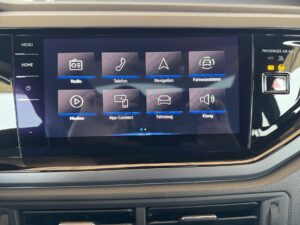 Touchscreen im Auto mit Symbolen für Radio, Telefon, Navigation. Schwarzer Hintergrund, glänzend.