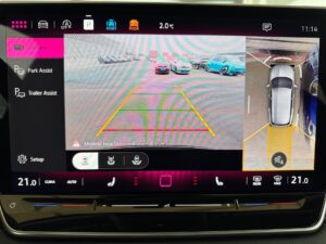 Bildschirm eines Fahrzeugs zeigt Rückfahrkamera-Ansicht mit Parklinien und Assistenzfunktionen.