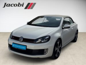 Silberner VW Cabrio, geschlossen, Sportfelgen, im Showroom mit "Jacobi"-Logo oben links.