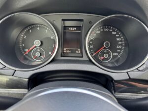 Armaturenbrett eines Autos mit Tachometer, Drehzahlmesser und digitaler Uhr, zeigt 13:27 Uhr.