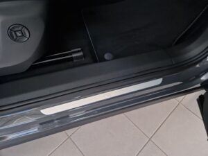 Grauer Auto-Innenraum mit silbernem Türschweller und dezenter Emblemgravur.